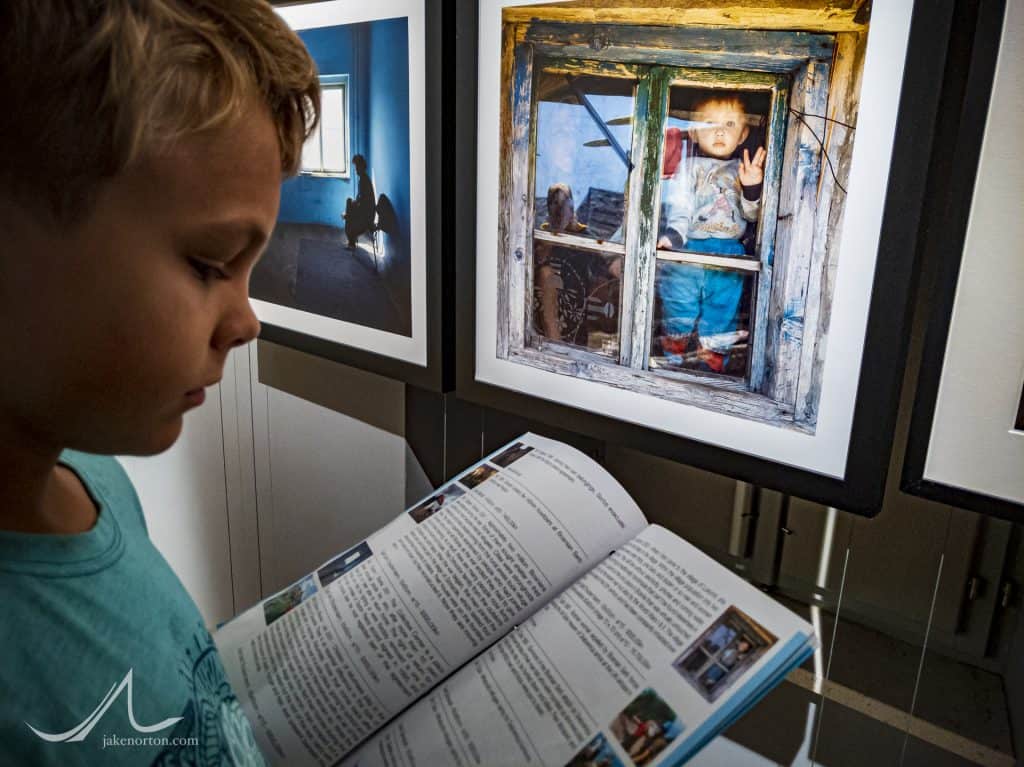 Ryrie Norton reads about the images on exhibit in the War Photos Exhibit, Dubrovnik, Croatia.